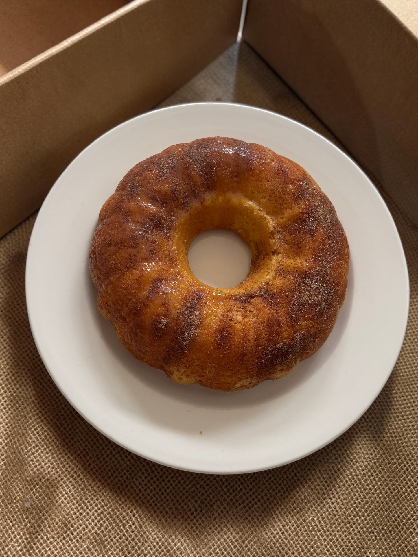 Donut Bouquet Canberra cinnamon donut cake on a white plate, featuring a golden-brown ring shape.