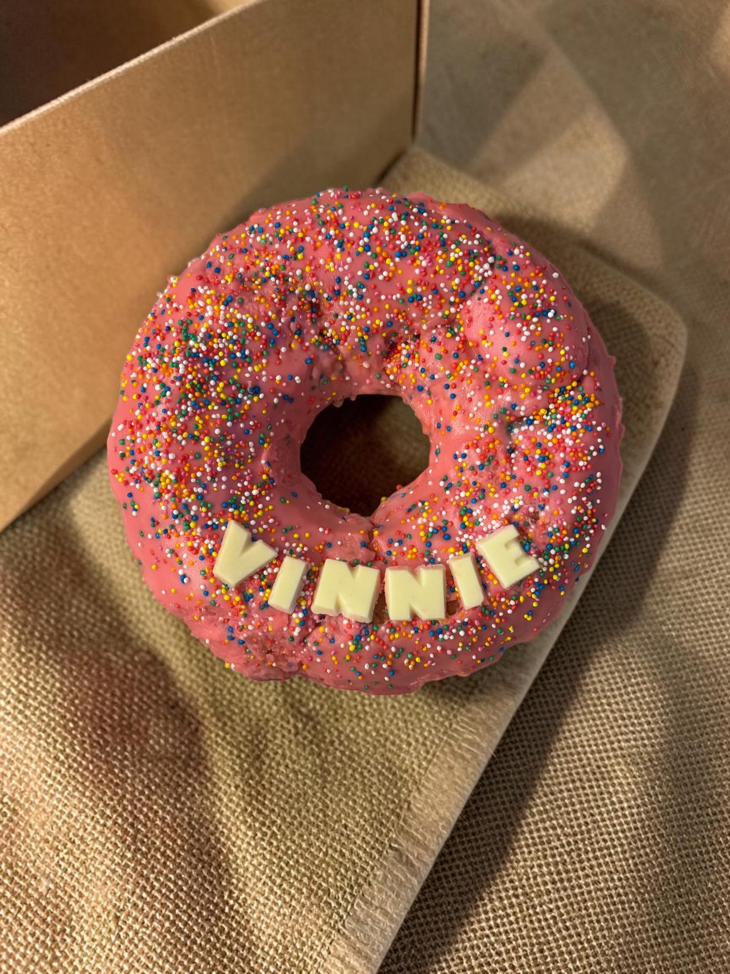 Donut Bouquet Canberra gluten free donut cake with pink icing, rainbow sprinkles, and white chocolate name topper
