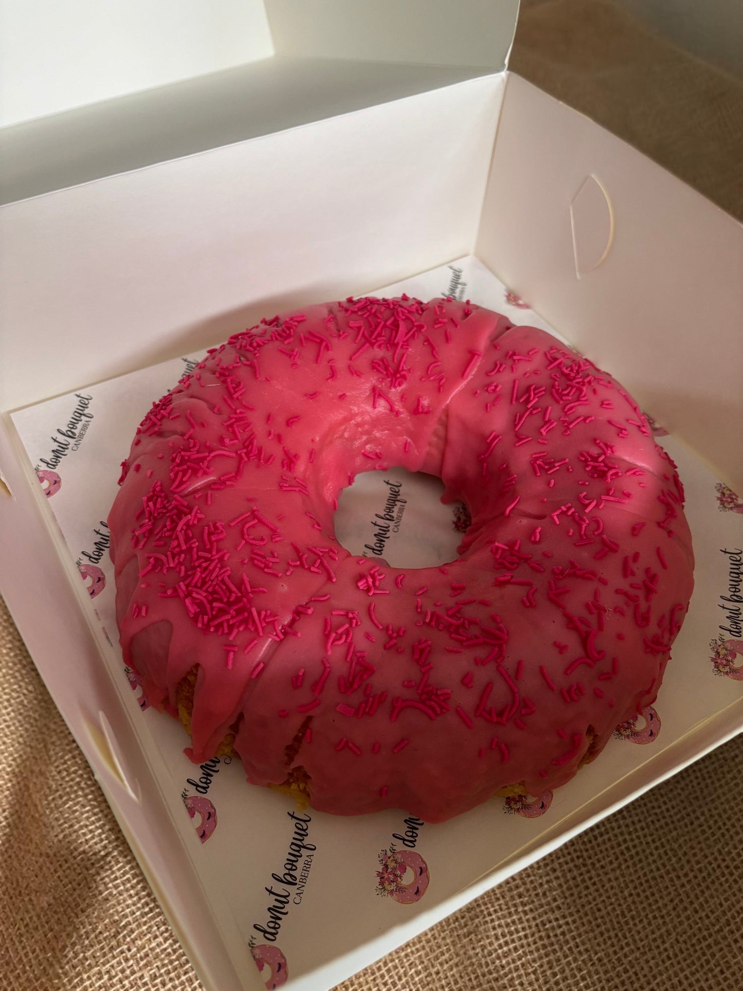 Donut Bouquet Canberra donut cake with bright pink icing and matching sprinkles in a branded white gift box