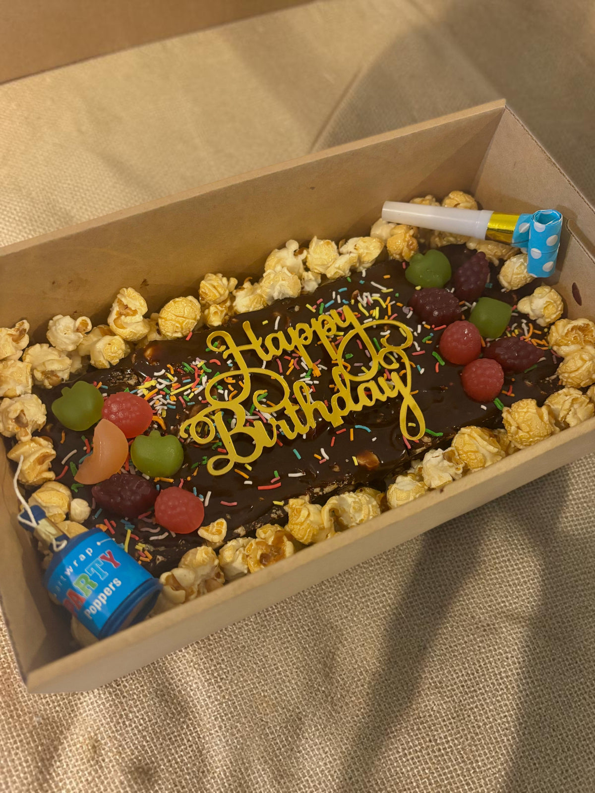 Donut Bouquet Canberra gluten free birthday brownie block topped with popcorn, chocolates, lollies, and sprinkles.