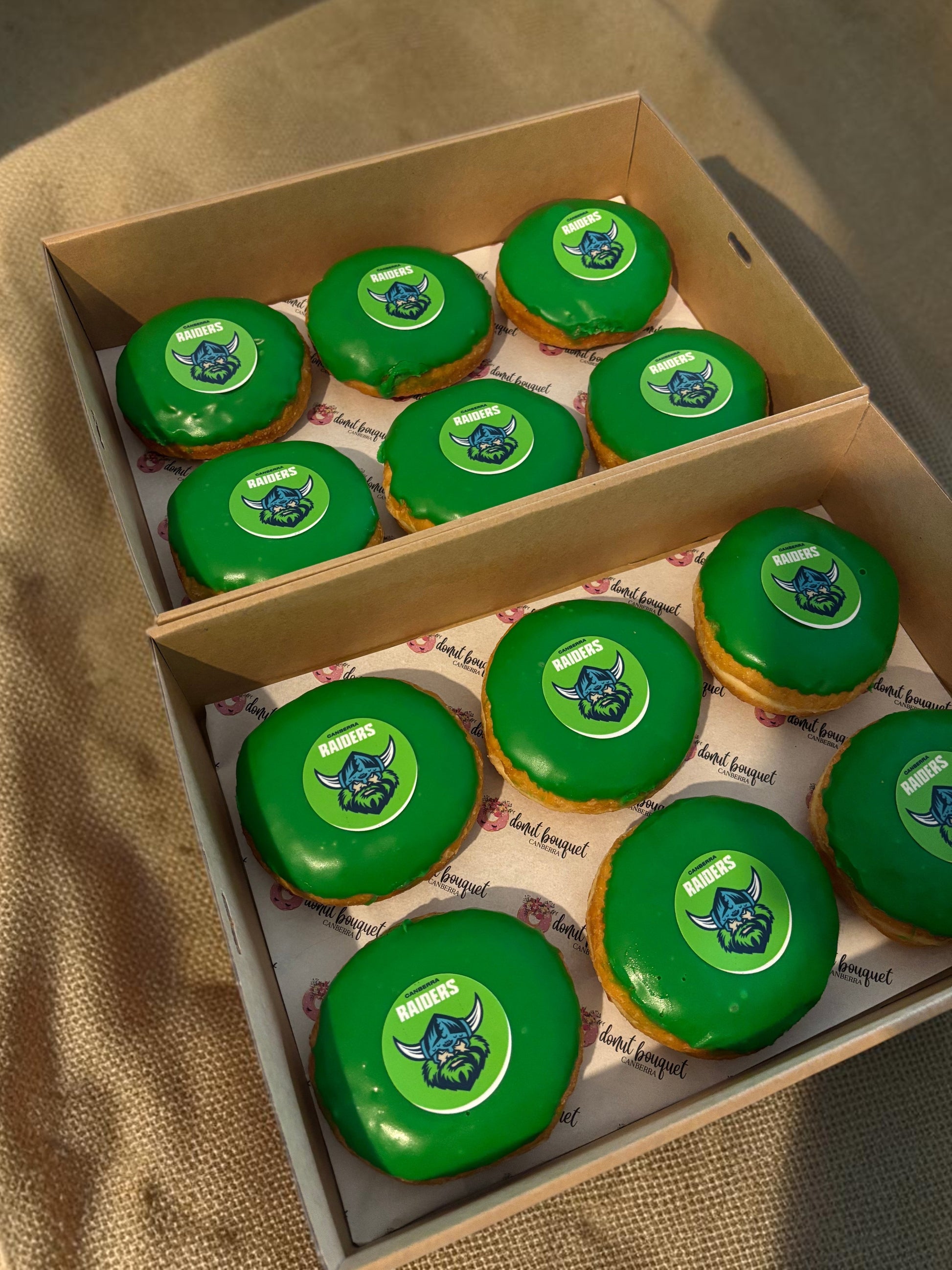 Donut Bouquet Canberra green glazed donuts arranged in rows inside cardboard boxes for a Raiders themed celebration.