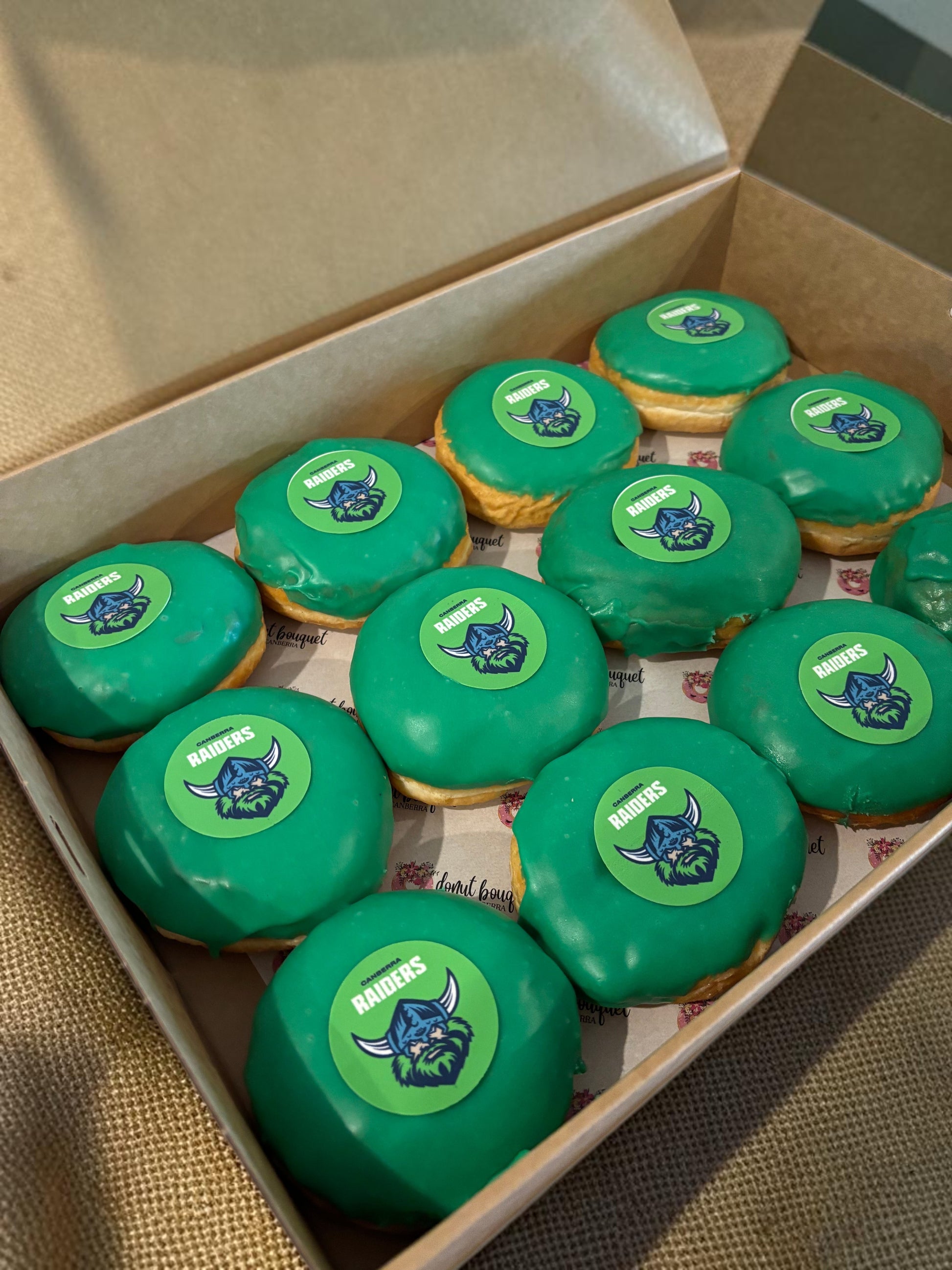 Donut Bouquet Canberra green glazed donuts arranged in rows inside cardboard boxes for a Raiders themed celebration.