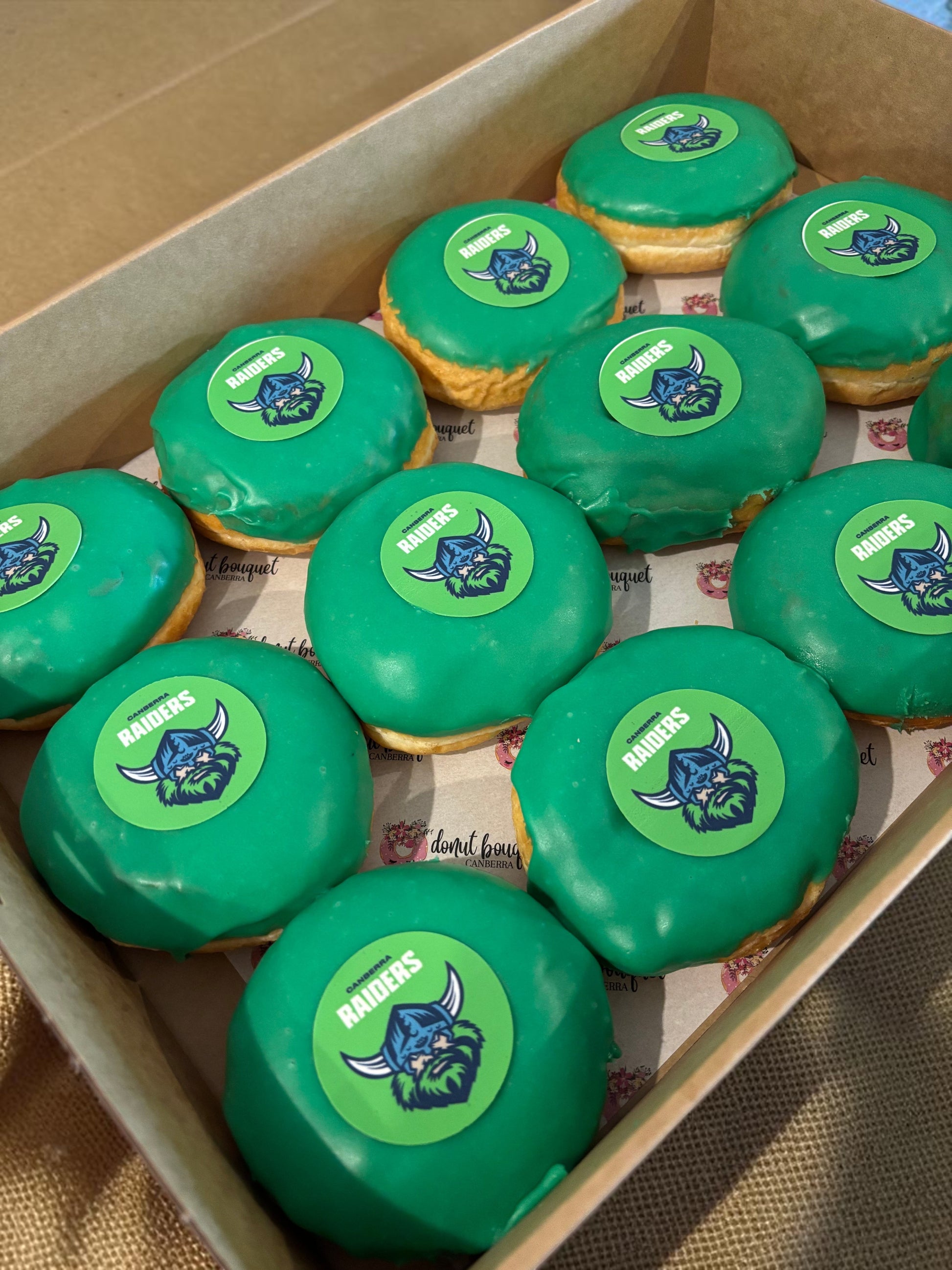 Donut Bouquet Canberra green glazed donuts arranged in rows inside cardboard boxes for a Raiders themed celebration.