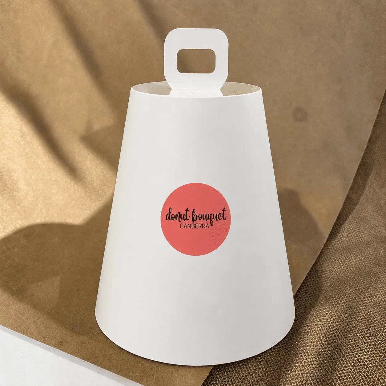 Donut Bouquet Canberra white protective cover for high tea gift set with handle on a brown textured background