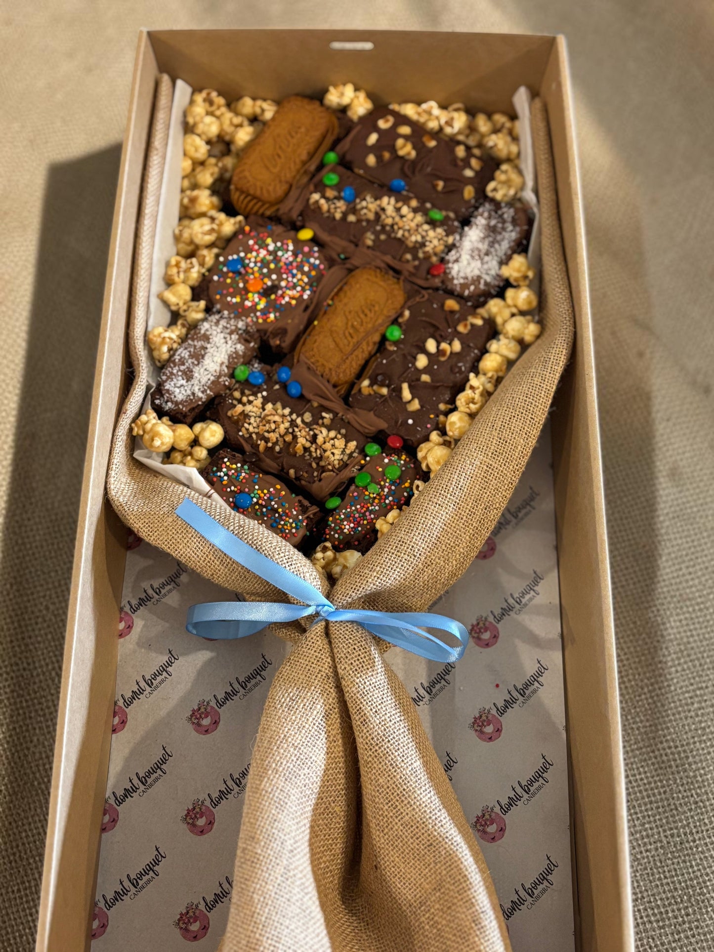 Donut Bouquet Canberra large loaded brownie bouquet gift box with chocolates, popcorn, and biscuits in a hessian wrap.
