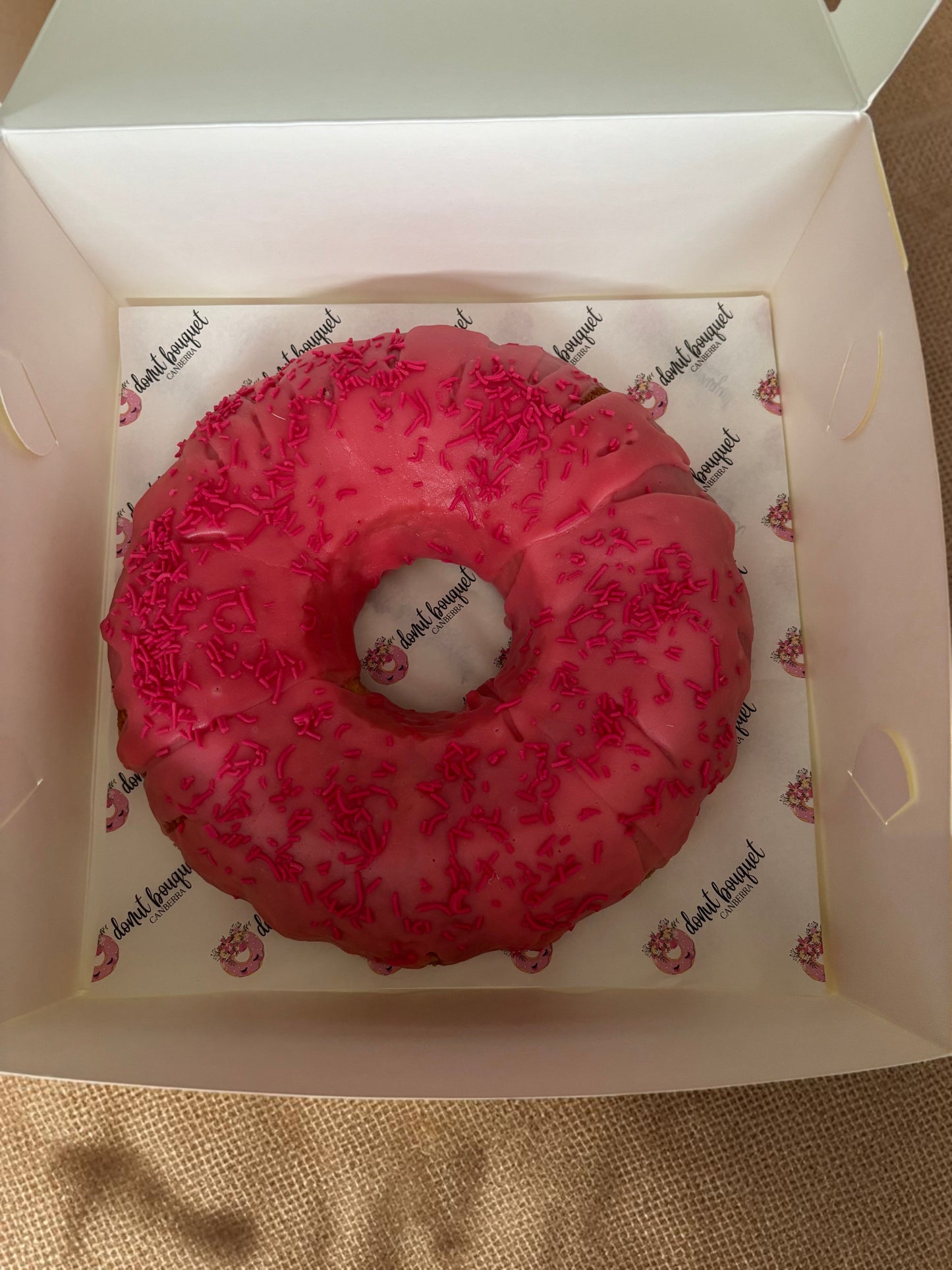 Donut Bouquet Canberra donut cake with bright pink icing and matching sprinkles in a branded white gift box
